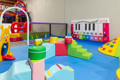Colorful indoor play area with soft climbing blocks and a piano wall.