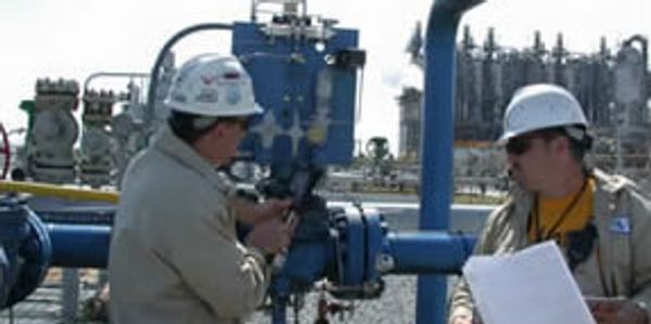 Two persons reviewing checklist for piping audit at industrial site.