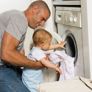 Dad and son in front of washer. 