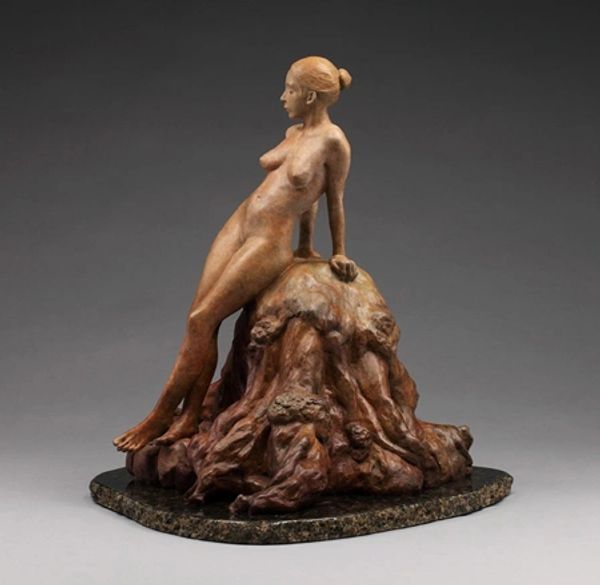Artwork and statue of a naked woman standing on a rock
