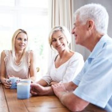 Three elderly people having a conversation over coffee.