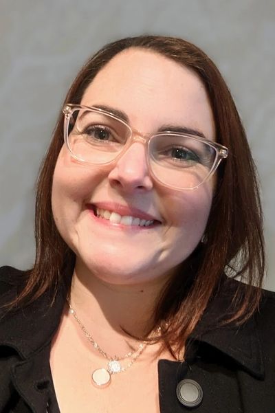 Femme souriante avec lunettes transparentes et collier.