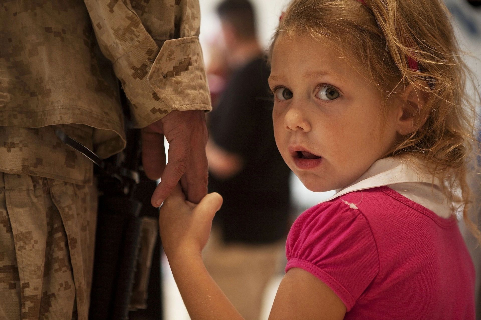 Little girl holds hand of father, a soldier