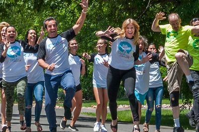 Our team running down a sunny, tree-lined street, smiling and jumping in our talk to the camera Tees