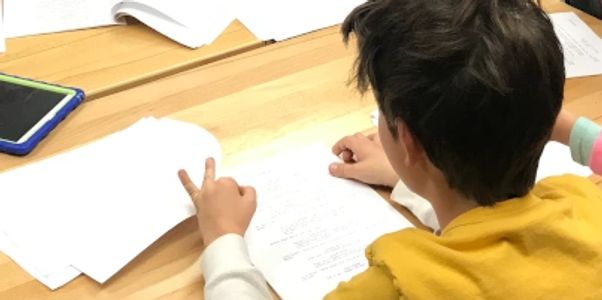 A group of young students and one of our instructors doing a script read at a desk.