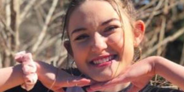 Headshot of one of the Talk to the Camera Brand Ambassadors. She's smiling, her hands below her chin