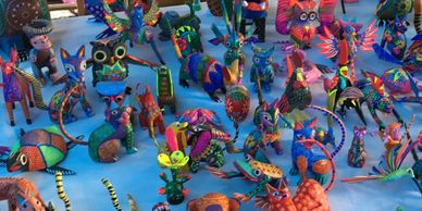 Pictured a table Alebrijes: Mexican folk art animals hand carved and painted from Oaxaca, Mexico.