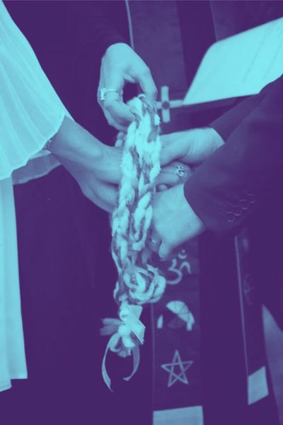 Wedding officiant wraps handfasting cord around bride and groom during wedding