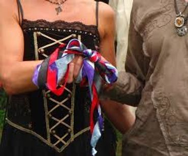 A couple performing the rite of handfasting during their wedding ceremony