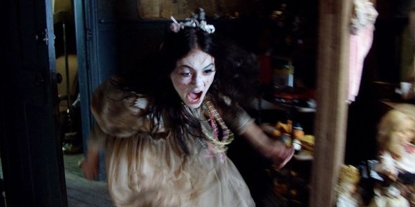 Ghost girl in toile dress with white face, screaming and lunging.