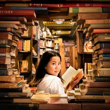 Uma mulher sorrindo dentro de uma biblioteca cercada de livros de abstemiologia
