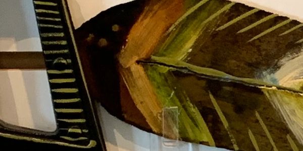 Close-up of a wooden paddle with green and brown paint.
