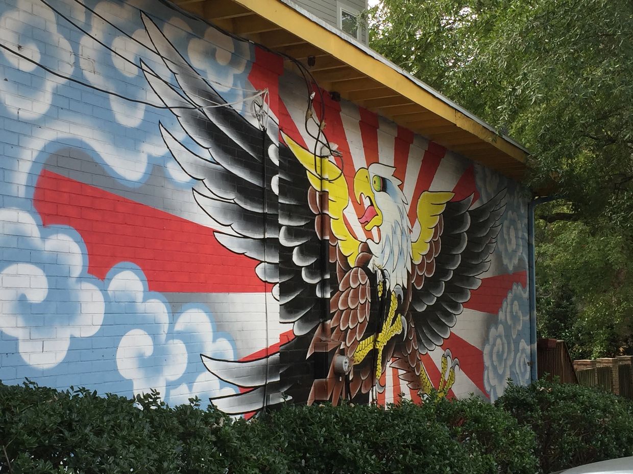 Mural with an eagle opening his wings on a red and white background with blue and white clouds.