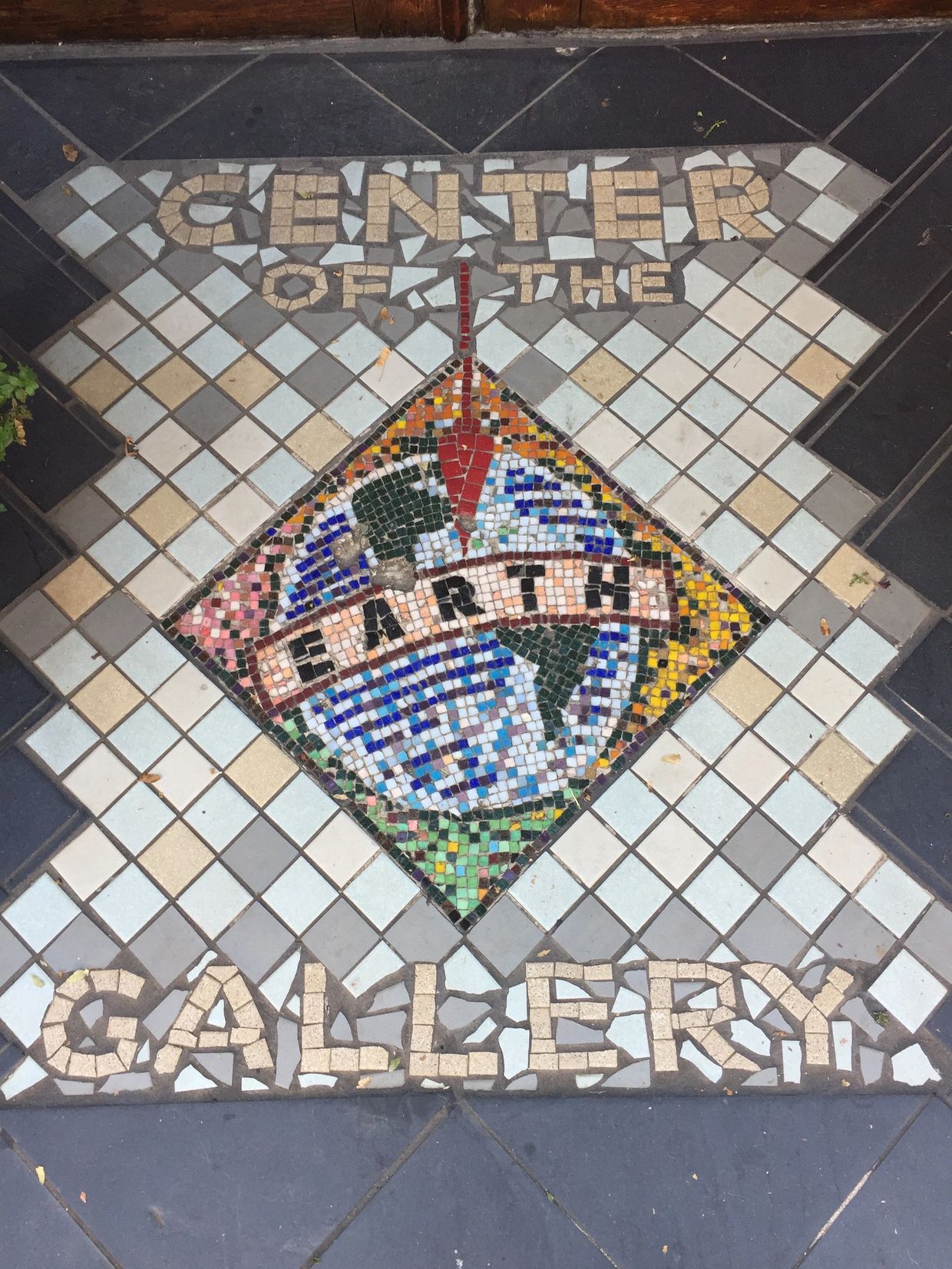 Mosaic floor design of a planet Earth with Center of the Earth Gallery spelled out in square tiles