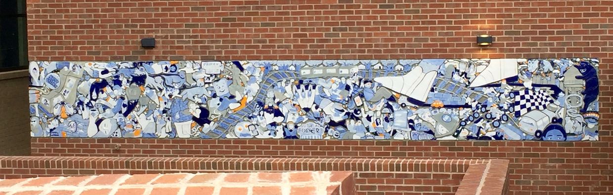 Mosaic relief mural full of ceramic imagery of Charlotte landmarks, signs, and various people.