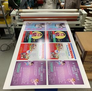 Applying a laminate to custom made vinyl posters while using a high production wide-format laminator