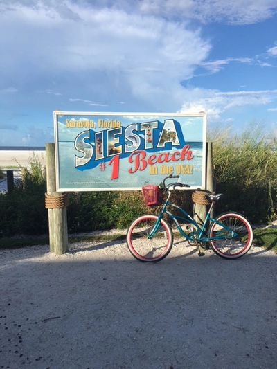 A sign at Siesta Beach that reads Siesta #1 Beach in the USA! A cruise bike leans against the side