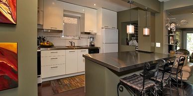 Green walls and lower kitchen cabinets, white kitchen cabinets, stainless steel island countertop.