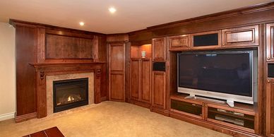 Red maple entertainment unit and surrounding cabinets, Wood fireplace mantel with cream marble,