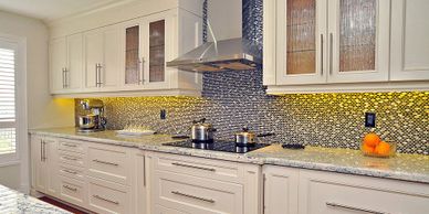Off white kitchen cabinets with quartz countertop, stainless steel chimney range hood, drop in stove
