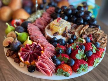 Charcuterie Board with an assortment of meat, cheese, and fruit with Brie wheel and honeycomb. 