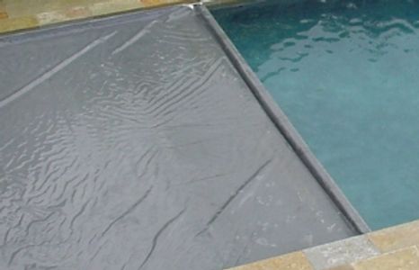 A partially covered swimming pool with a safety cover.