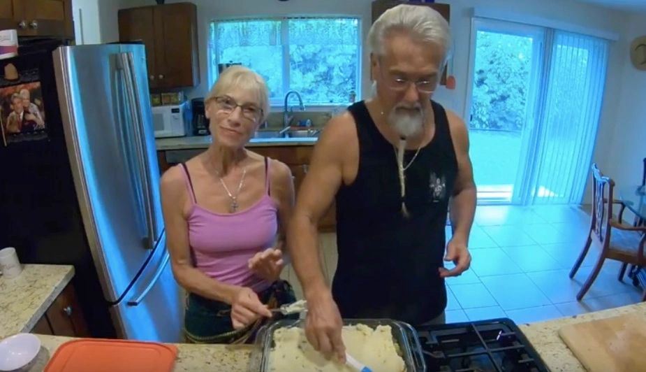 Middle-aged couple preparing food together in a kitchen.
