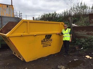12 yard skip for hire with man standing next to it.