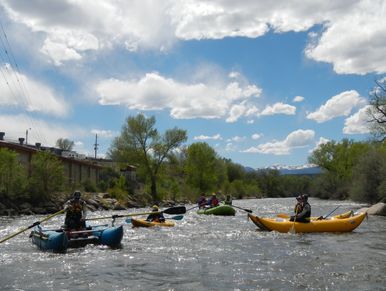 Rafts & kayaks boating on the Arkansas River, blue sky and fluffy clouds.
