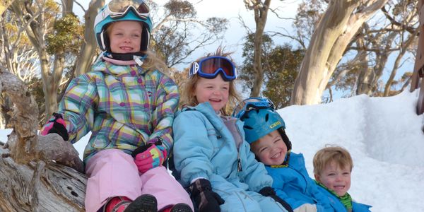 kids sitting on log in snow