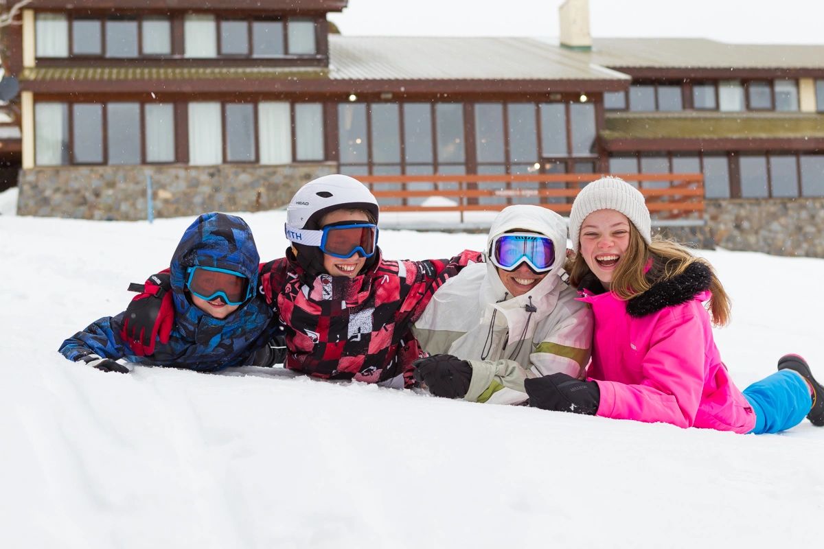 family laying on the snow outside Valhalla Lodge Perisher