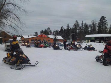 Snowmobiles parked outside Crane Lake Bar and Grill during winter.