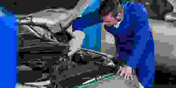 Car mechanic wearing glove fixing engine working under the hood of the car