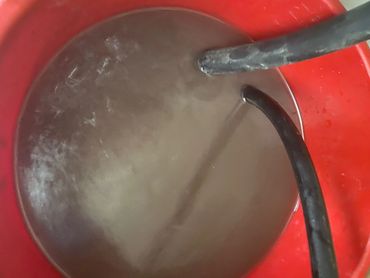 Bucket of murky solution from tankless water heater maintenace