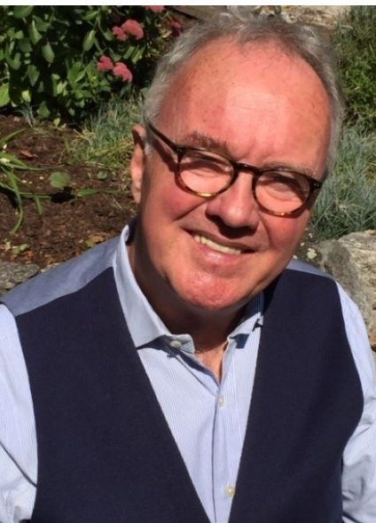 Smiling elderly man in glasses outdoors.