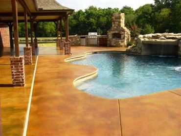 tan concrete around swimming pool with brick oven