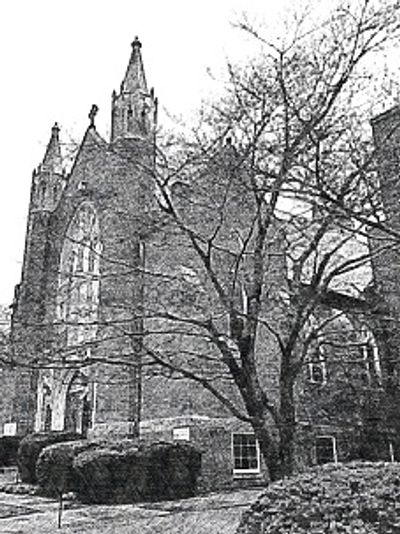 A large stone church with tall spires and leafless trees in front.