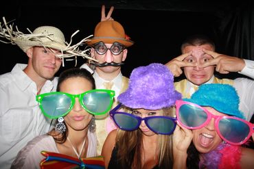 people wearing funny hats and big glasses inside a photo booth