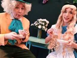Two people dressed as Mad Hatter and Alice enjoying tea.