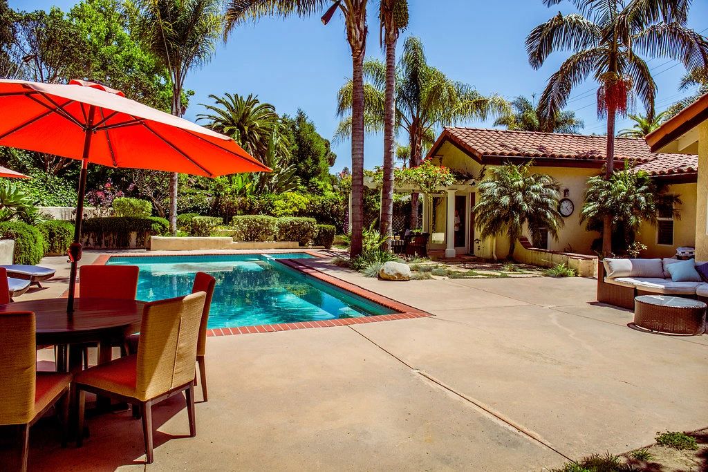 Exterior of a home's backyard with a pool and patio furniture.