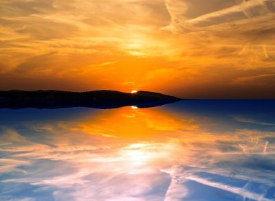 Sunset over a calm water body with reflections.