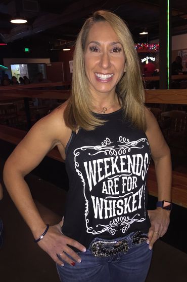 Woman smiling in a black tank top that says 'Weekends Are For Whiskey'.