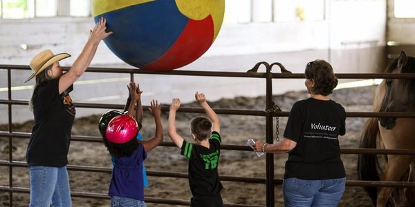 Stacey Harnew, student,volunteer playing with horses during horse session. Wild Horse Mountain Ranch