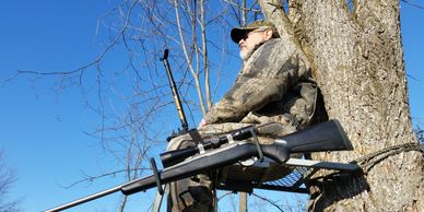 Hunter in a tree stand with a Hip Stick Shooting Rest on his leg and a Gun Holder at his side