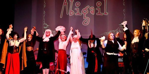Cast of original live production on a stage.