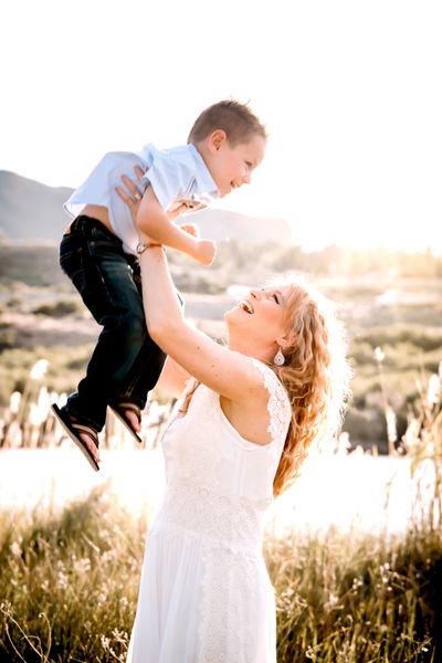 Natalie raising her son in the air laughing.