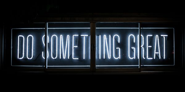 Neon sign glowing with the phrase 'DO SOMETHING GREAT'.
