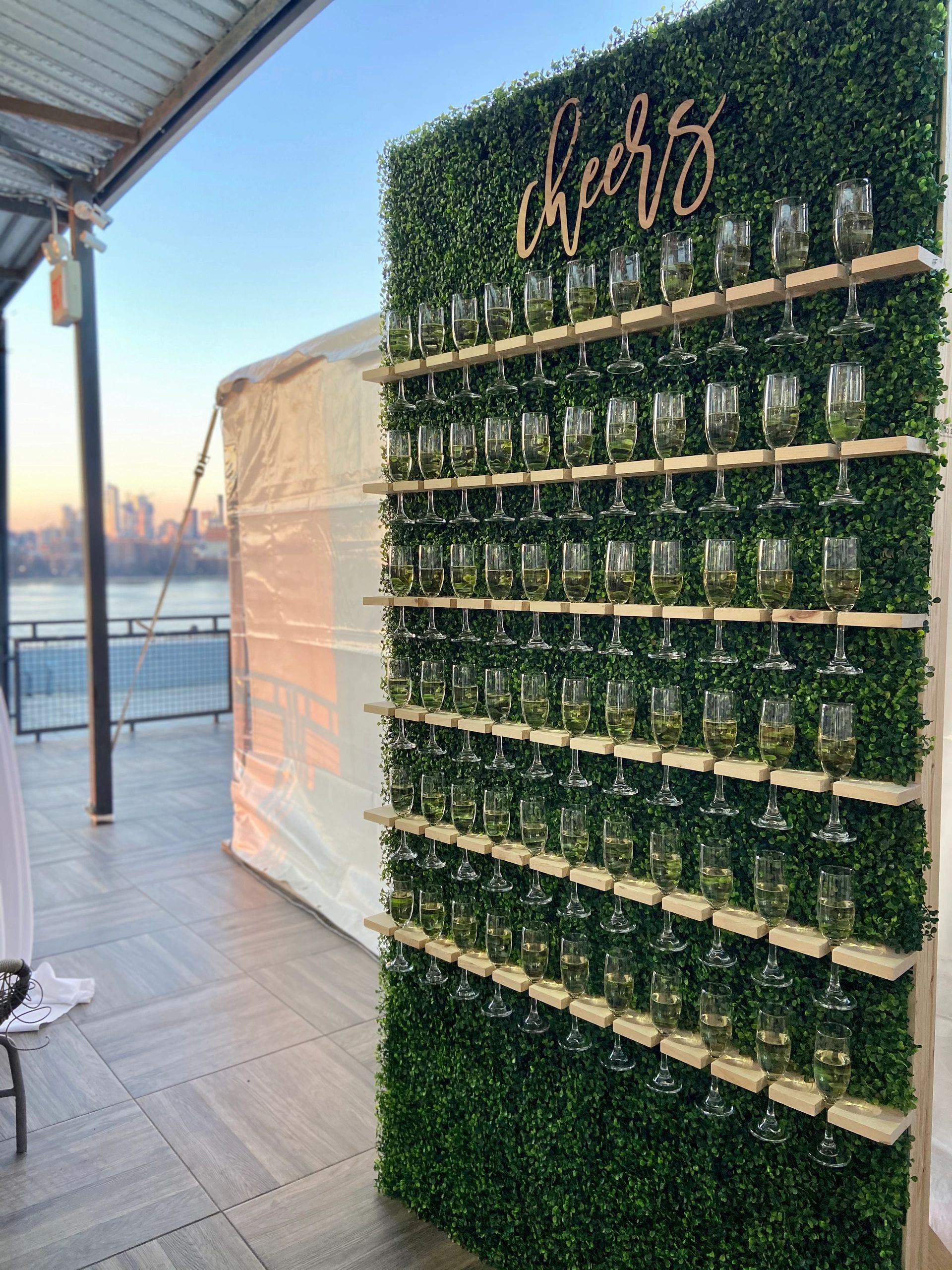 This is a picture of a green champagne wall withe 66 champagne glasses on it in front of the New Yor