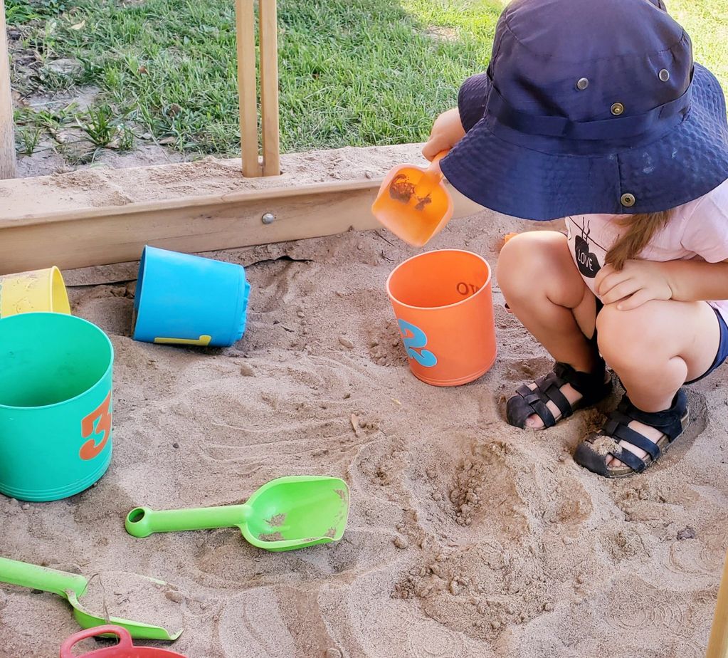 Child in sandbox with scoops and buckets