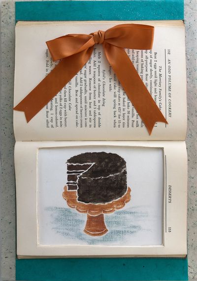 A book with a print of a chocolate cake inserted and framed.